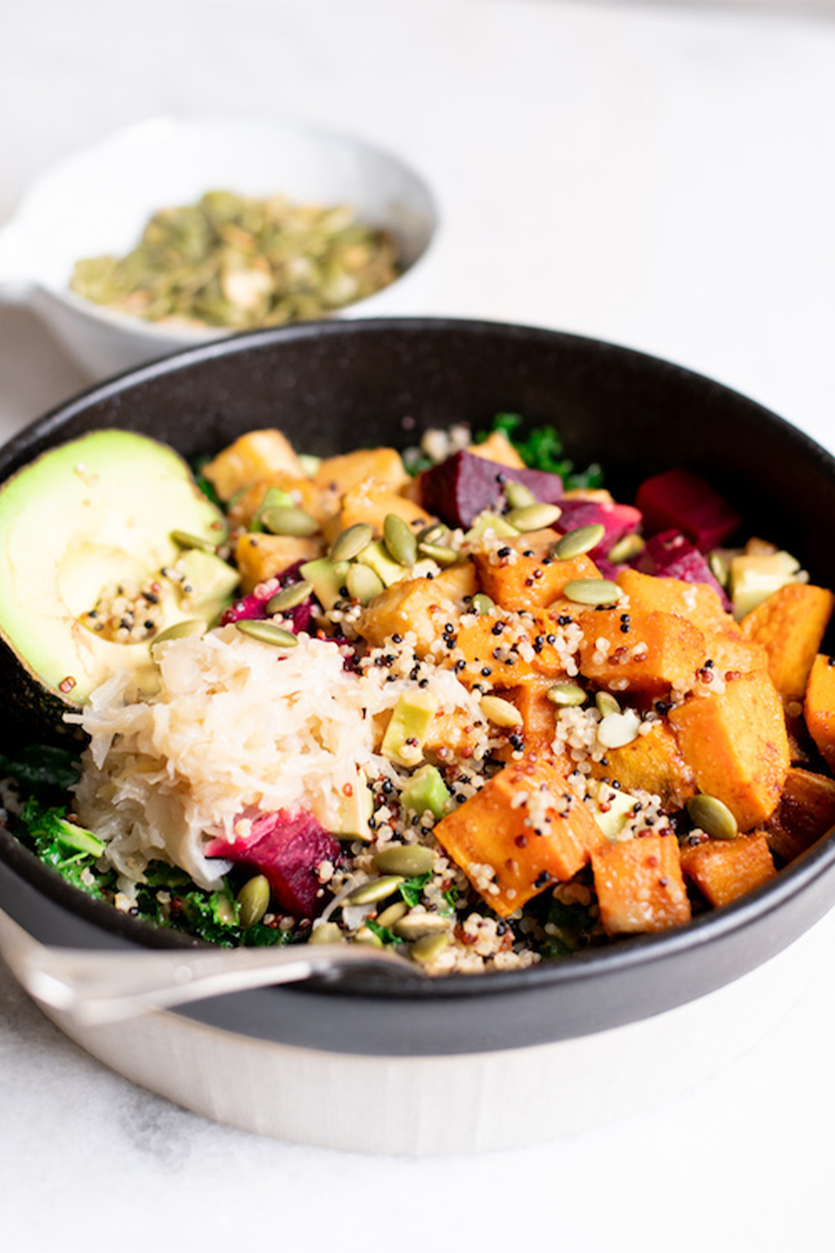 a vegan macro bowl with potatoes, pumpkin seeds, greens and sauerkraut