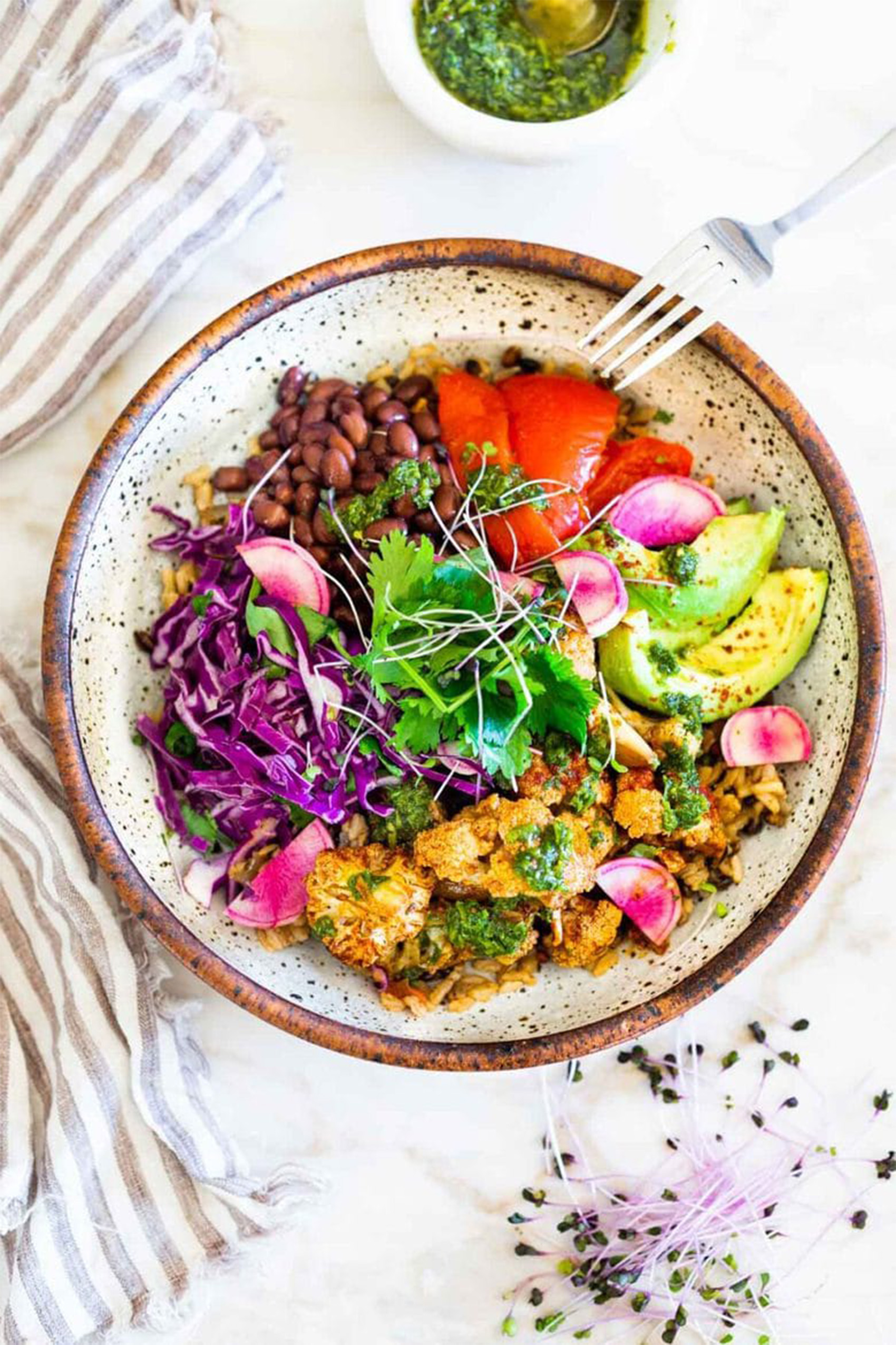a vegan nourish bowl with black beans, cabbage, avocado, herbs and sauteed veggies