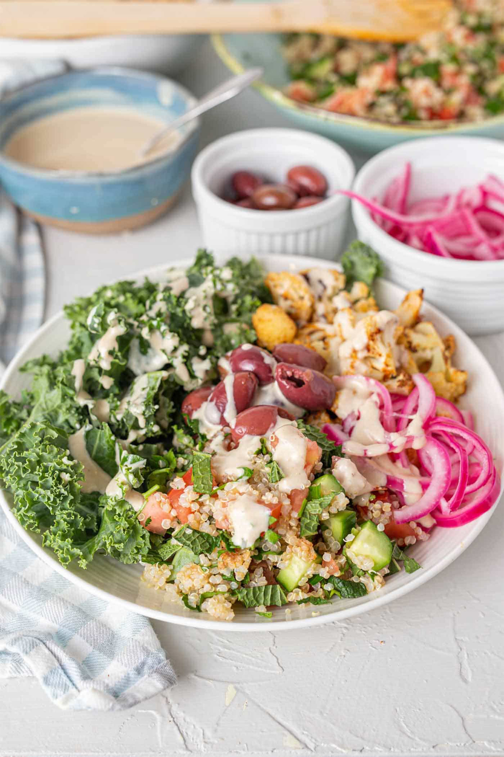 a bowl of kale, vegan tabouli, pickled onions and olives