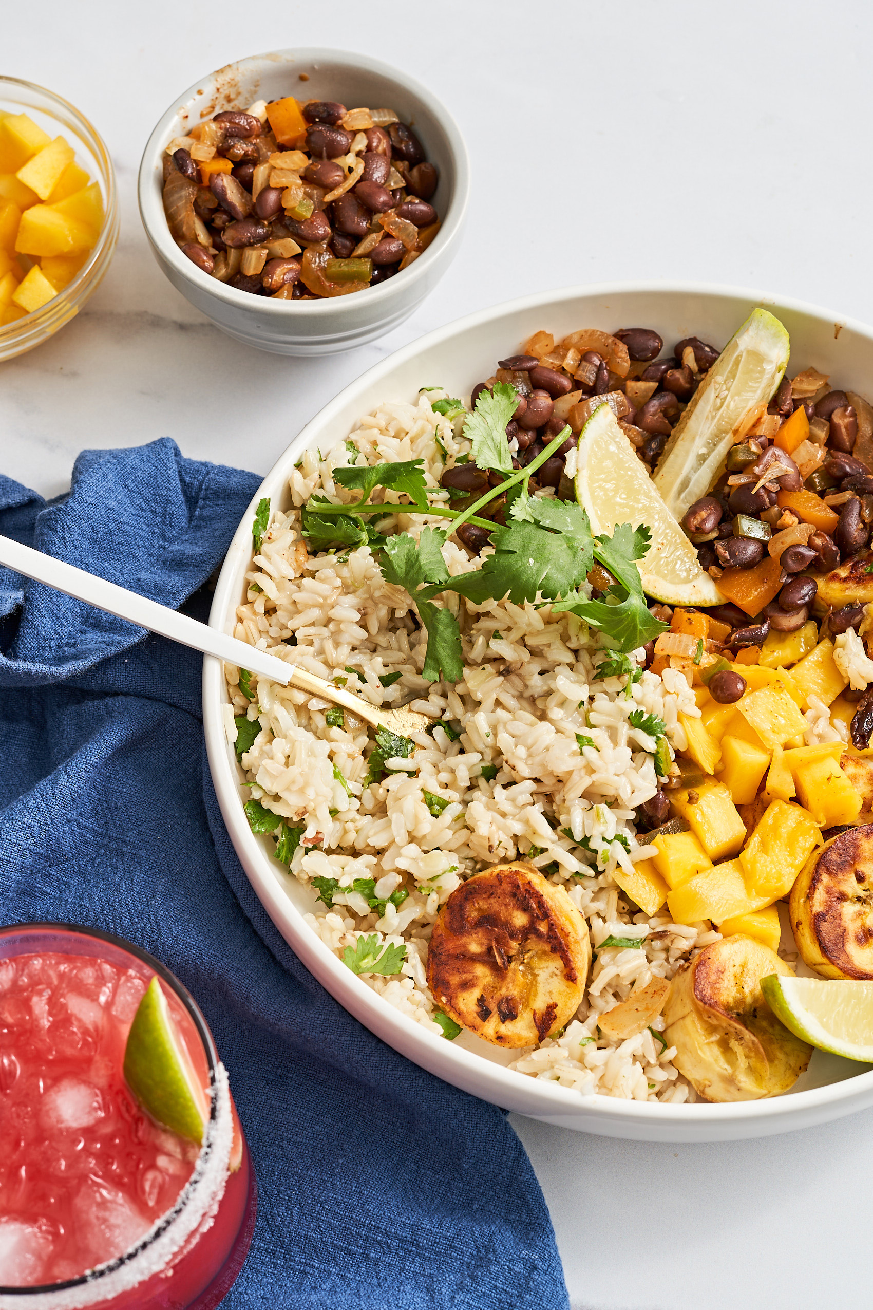 a bowl of brown rice served with black beans, mango and plantains