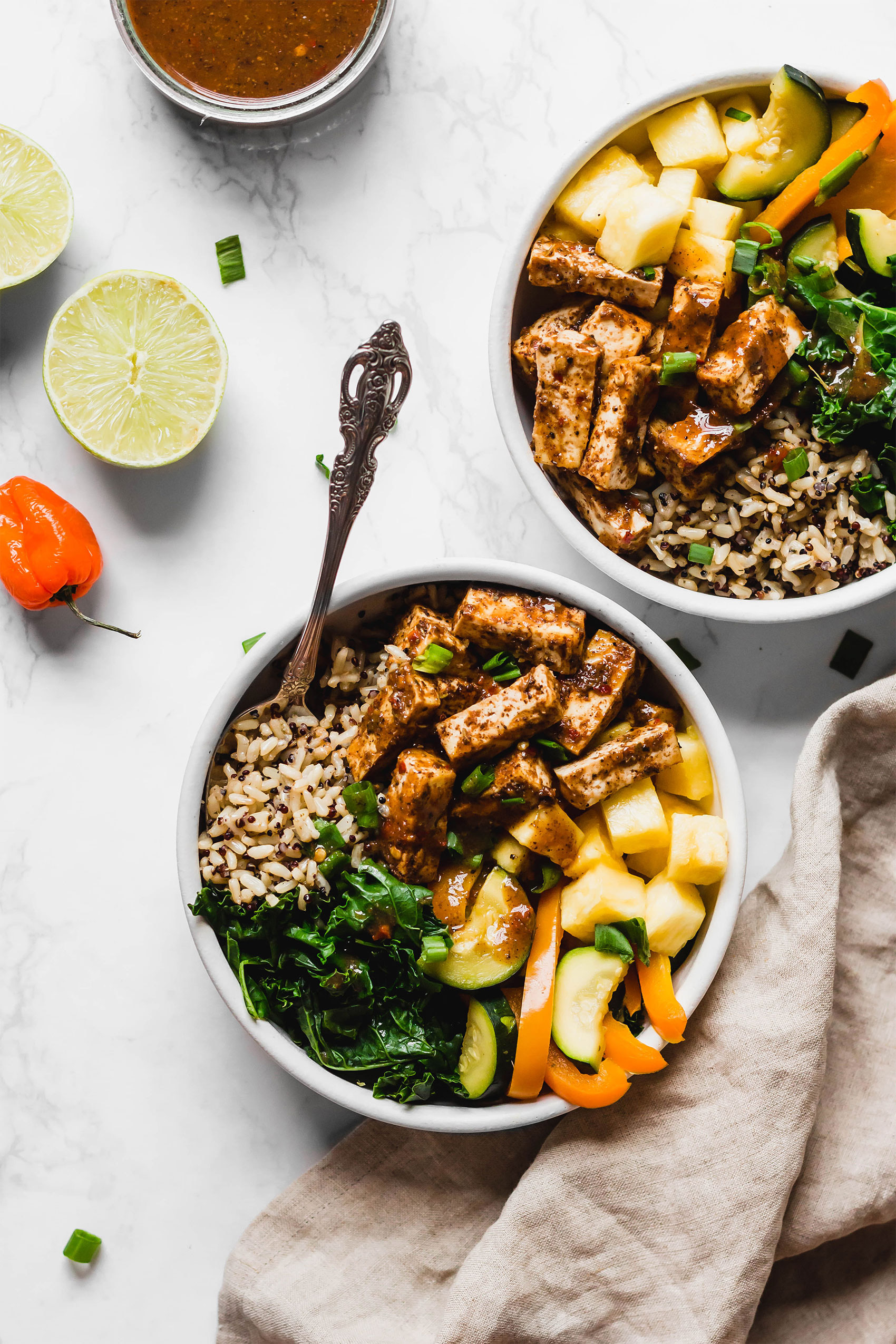 two Jerk tofu bowls with pineapple, greens and veggies