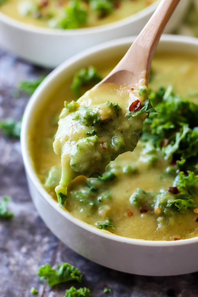 a spoon taking a scoop of vegan potato kale soup
