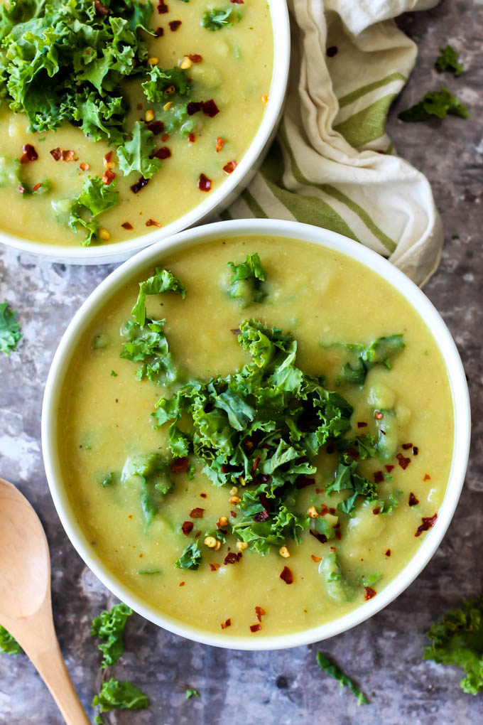 two bowls of potato kale soup topped with red pepper flakes