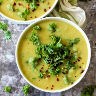 a bowl of potato soup topped with kale and red pepper flakes