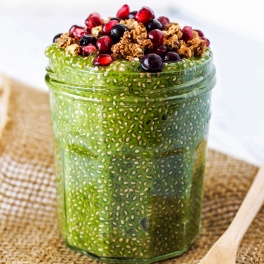 a jar filled with matcha chia pudding topped with pomegranate seeds and granola