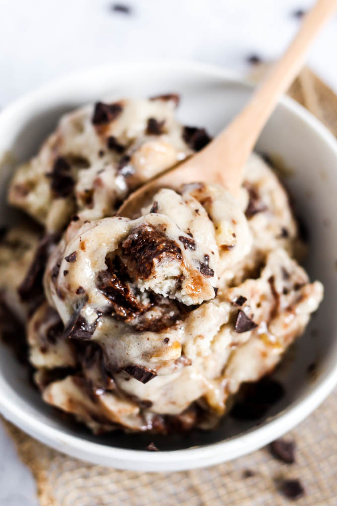 A spoon takes a bite out of a bowl of homemade vegan banana brownie bit ice cream