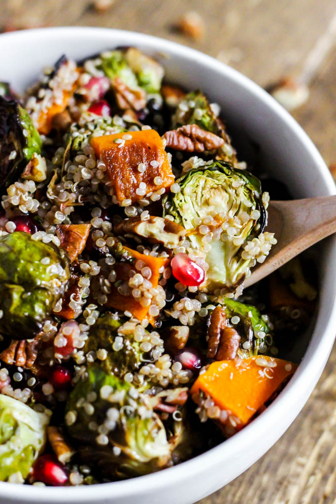 a bowl of quinoa with brussels sprouts, butternut squash, pecans, pomegranate seeds and a vinaigrette