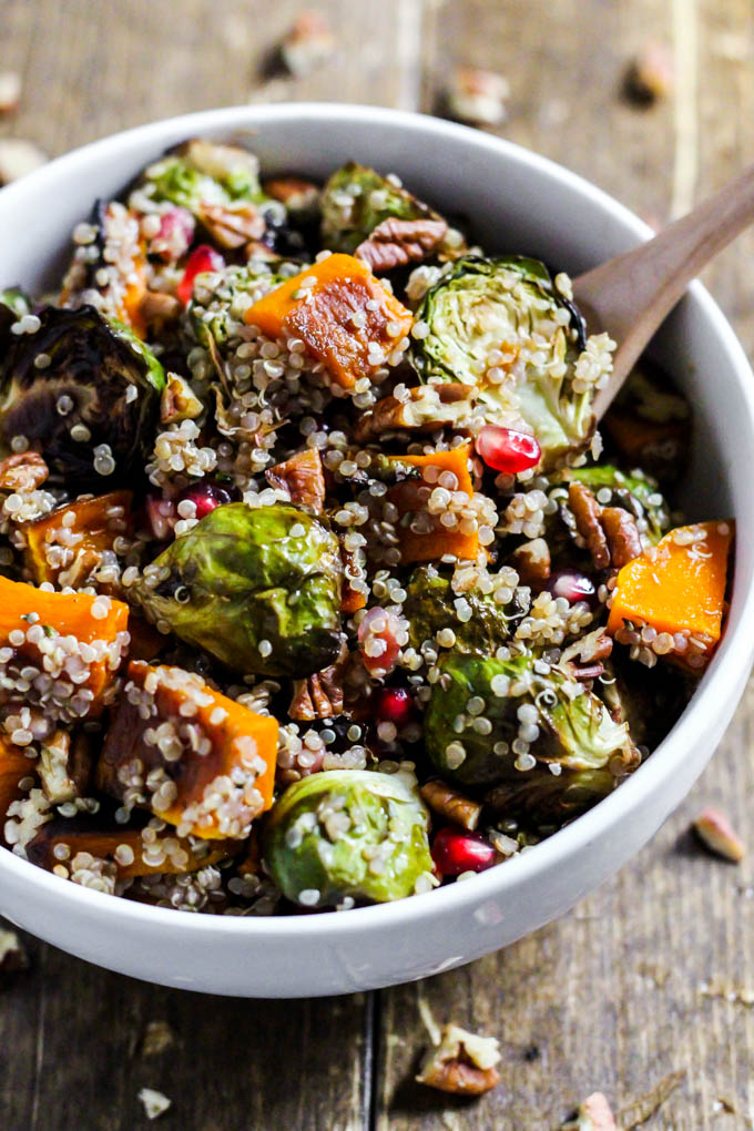 a bowl of quinoa salad with roasted veggies, pomegranate seeds and pecans