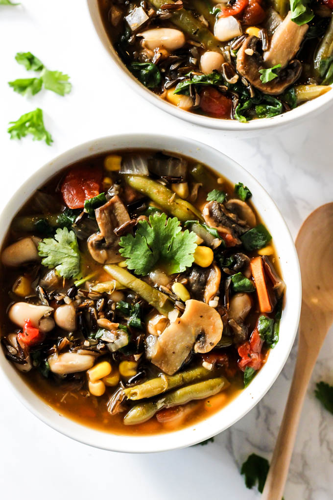 a bowl of wild rice soup with mushrooms, green beans, white beans, peppers, corn and carrots