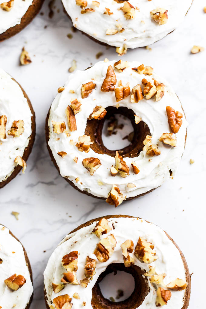 a batch of gingerbread donuts topped with coconut cream and crushed pecans