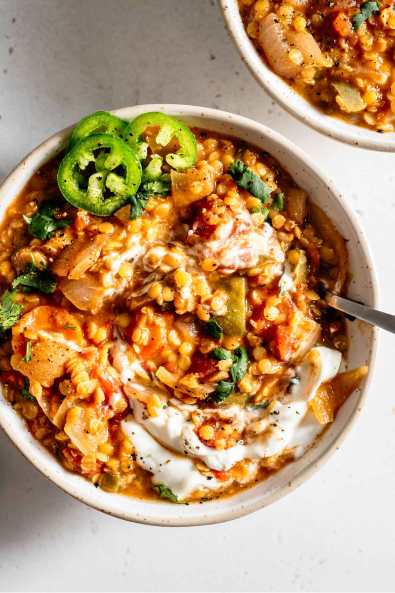 a bowl of red lentil chili served with fresh jalapeno slices