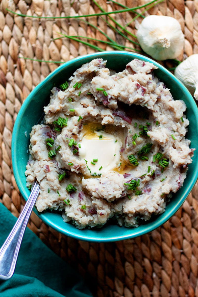 a bowl of mashed potatoes topped with chives and a pat of butter