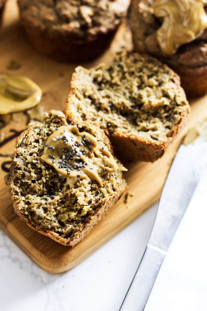 a banana muffin that has been sliced in half and topped with almond butter and chia seeds