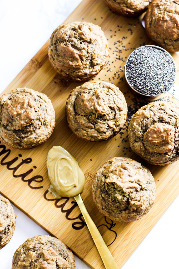 a batch of banana muffins served next to a cup of chia seeds and a spoon of almond butter
