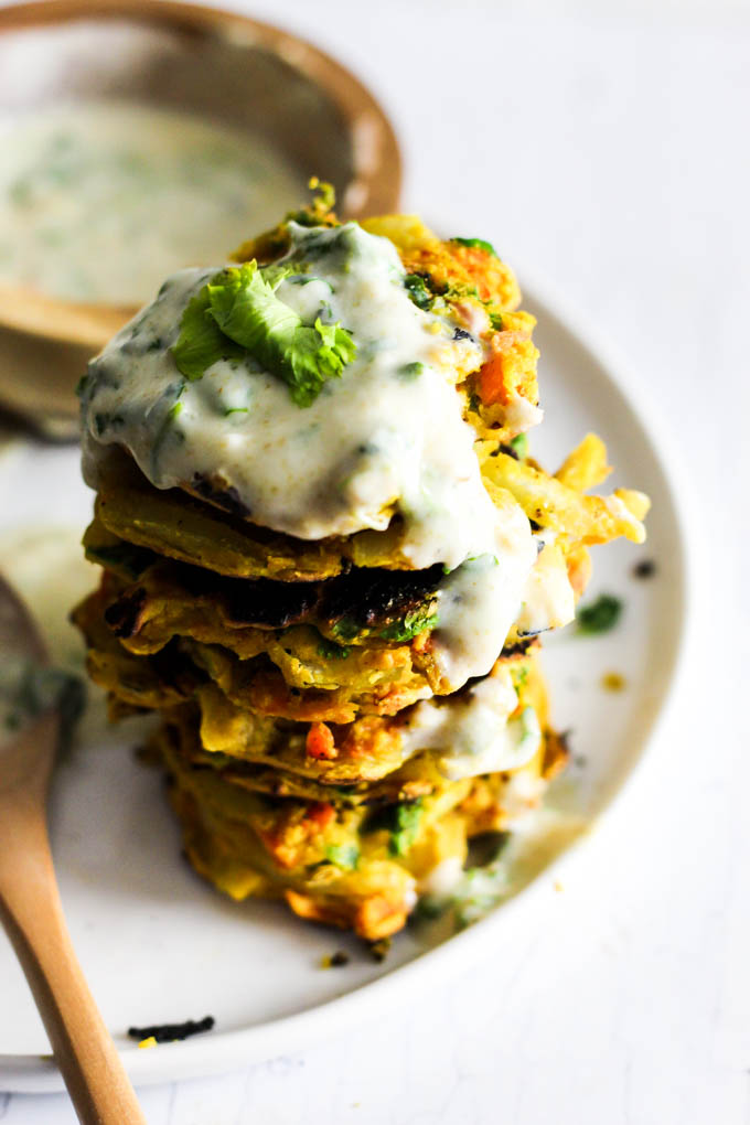 Add these Crispy Onion & Carrot Fritters to dinner for a flavorful, vegetable-packed side dish! A dollop of cumin yogurt tops it off. Vegan & gluten-free!