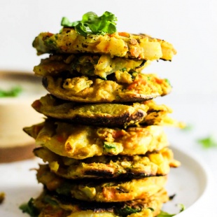 Add these Crispy Onion & Carrot Fritters to dinner for a flavorful, vegetable-packed side dish! A dollop of cumin yogurt tops it off. Vegan & gluten-free!