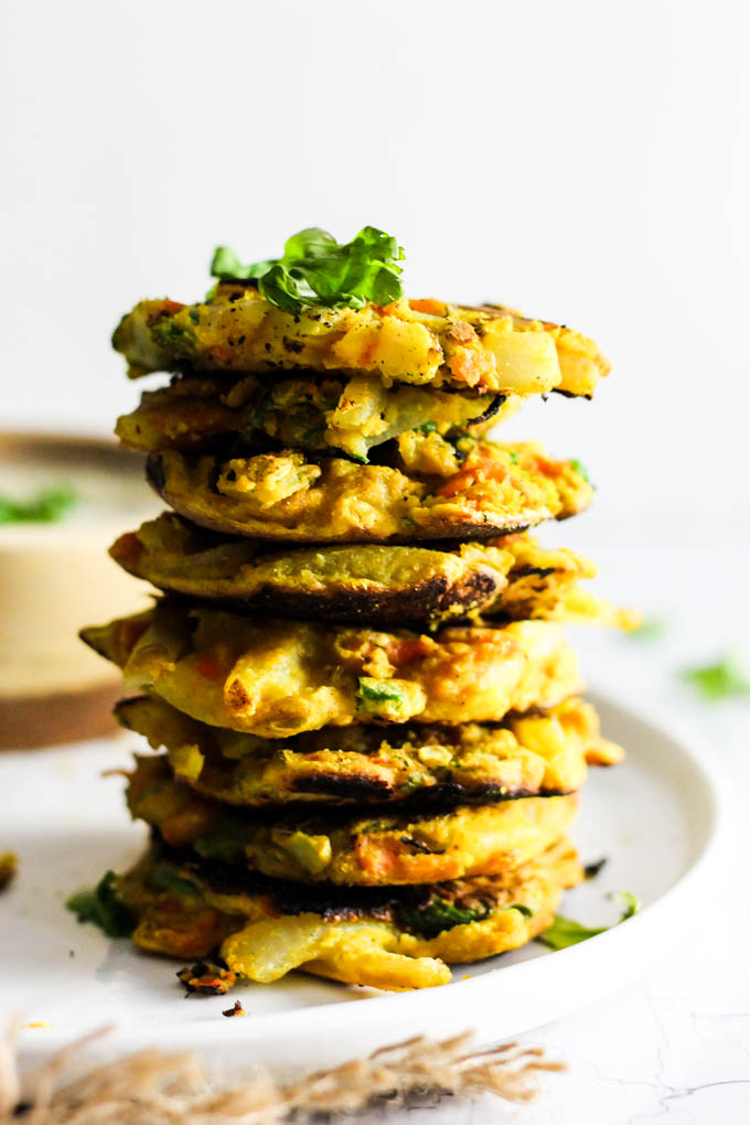 Add these Crispy Onion & Carrot Fritters to dinner for a flavorful, vegetable-packed side dish! A dollop of cumin yogurt tops it off. Vegan & gluten-free!