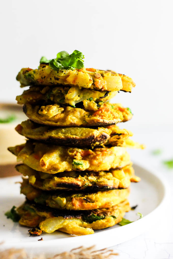 Add these Crispy Onion & Carrot Fritters to dinner for a flavorful, vegetable-packed side dish! A dollop of cumin yogurt tops it off. Vegan & gluten-free!