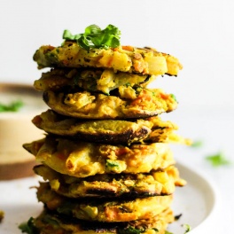 Add these Crispy Onion & Carrot Fritters to dinner for a flavorful, vegetable-packed side dish! A dollop of cumin yogurt tops it off. Vegan & gluten-free!