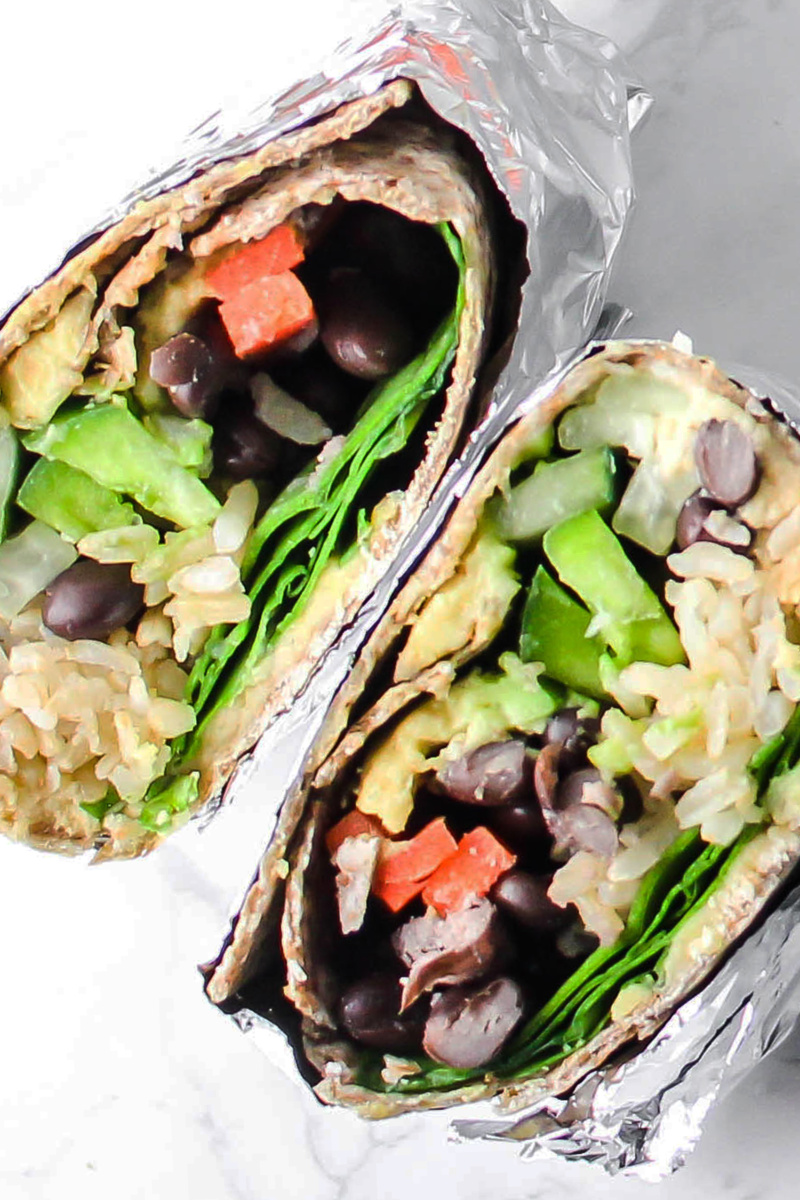 two halves of a veggie wrap stuffed with rice, beans and sliced vegetables