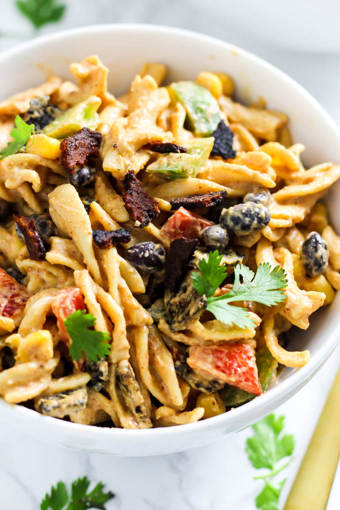 A serving of Mexican-inspired pasta salad topped with cilantro and vegan bacon