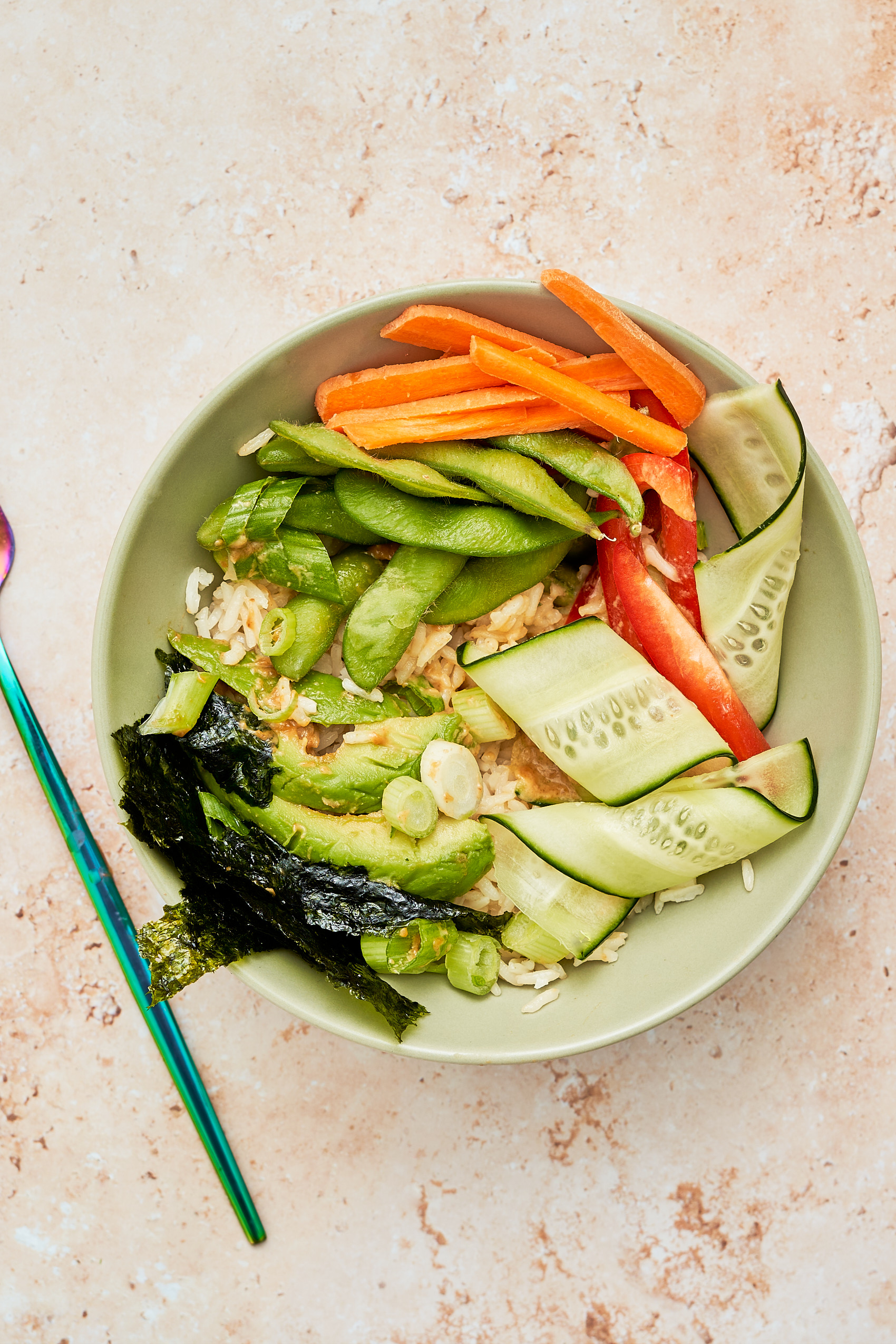 a lunch bowl featuring brown rice, edamame, carrots, bell pepper and avocado