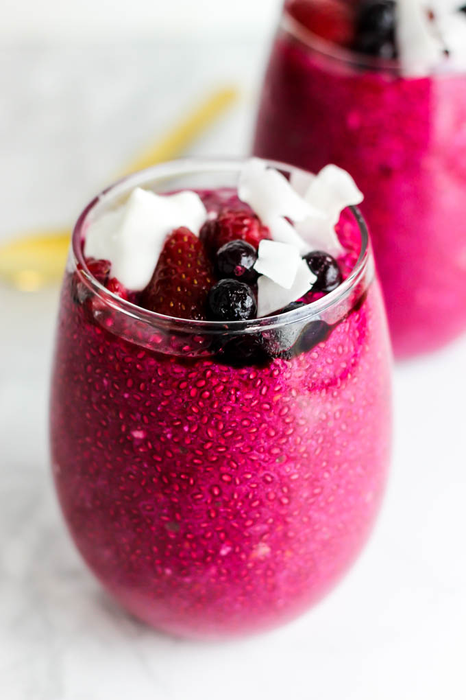 a serving of beet strawberry chia pudding topped with berries and coconut flakes
