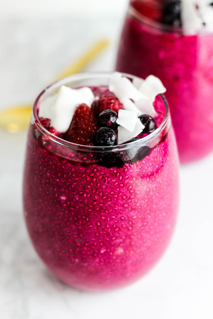 a serving of beet strawberry chia pudding topped with berries and coconut flakes