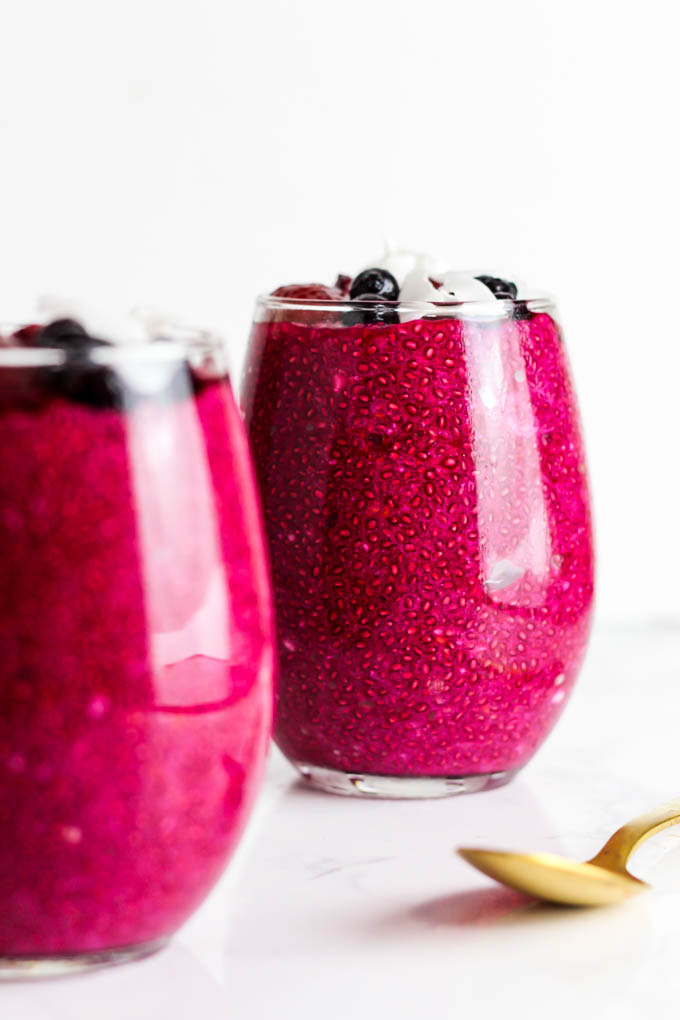 two servings of beet strawberry chia pudding topped with coconut flakes and berries