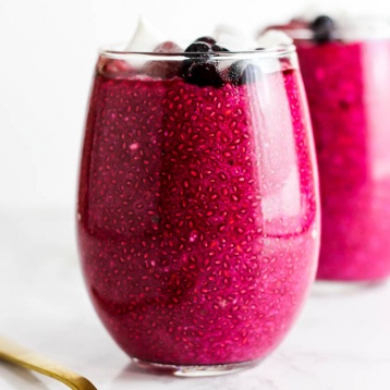 a cup filled with strawberry beet chia pudding topped with coconut flakes and fresh berries