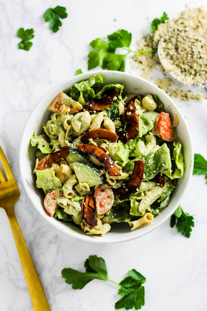 A serving of dairy-free pasta salad topped with coconut bacon and a sprinkle of hemp seeds