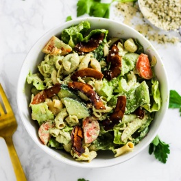 a bowl of vegan pasta salad topped with coconut bacon