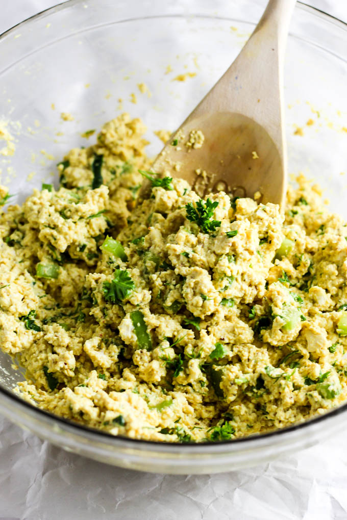 A bowl of vegan tofu egg salad with a wooden spoon