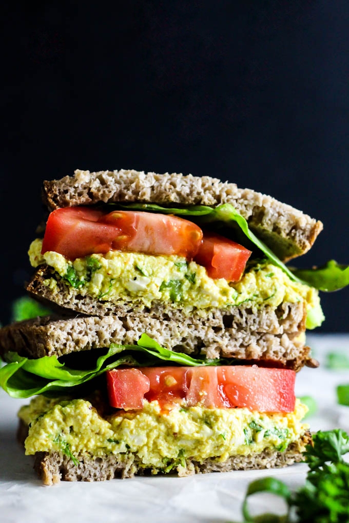 A tofu salad sandwich topped with sliced tomato and lettuce