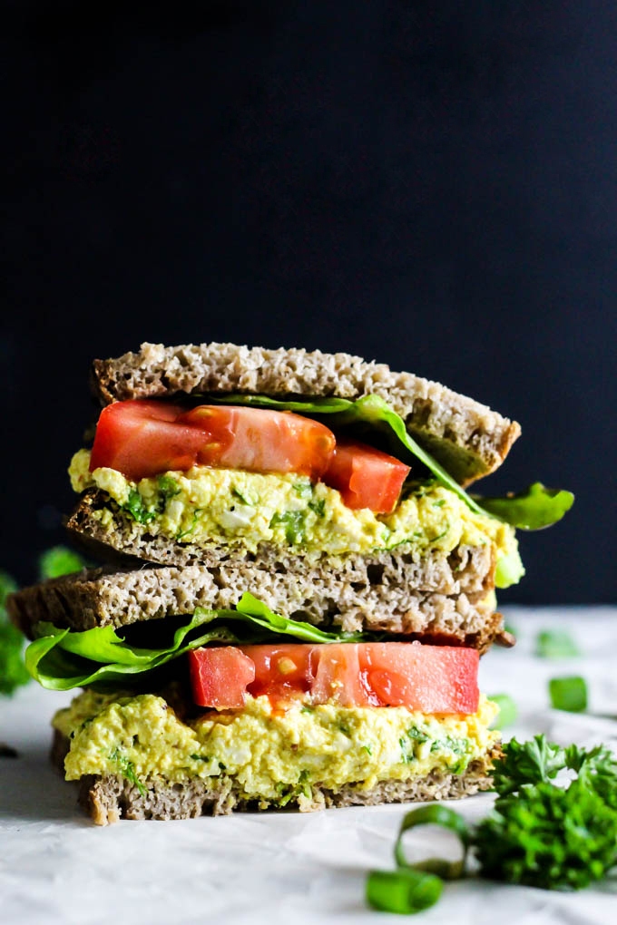 A tofu egg salad sandwich topped with lettuce and tomato