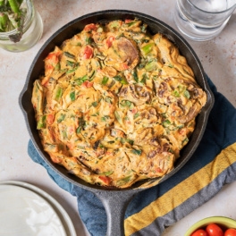 a vegan quiche filled with asparagus, mushrooms, tomatoes and greens served in a cast iron skillet