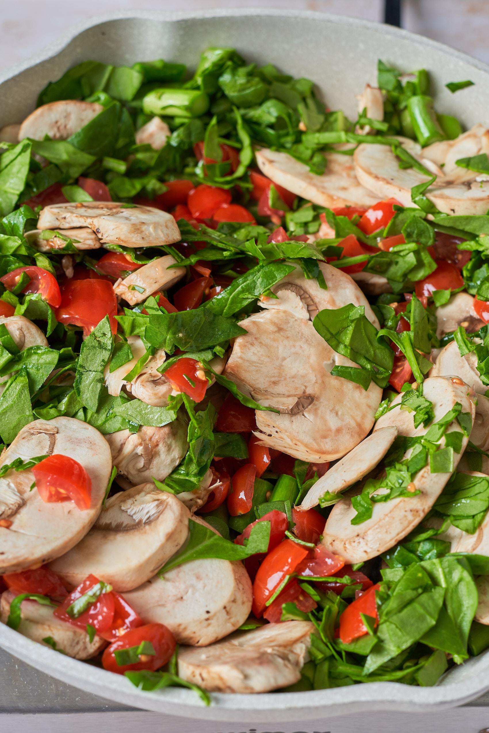 a closeup of sauteed greens, sliced mushrooms, tomatoes and asparagus