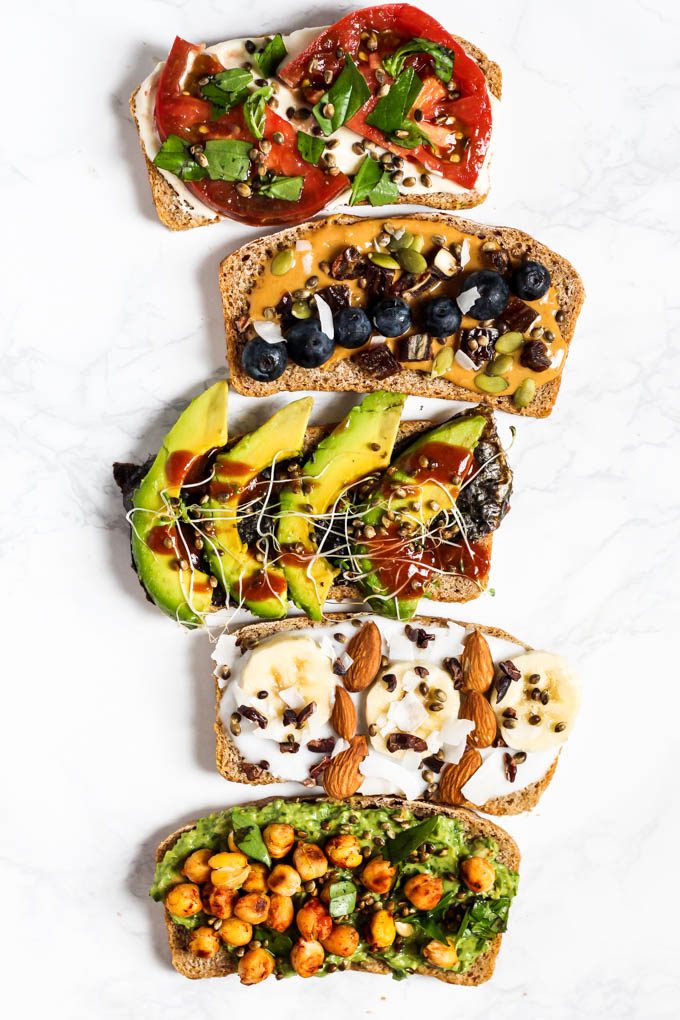 5 different topped toasts including a caprese toast, peanut butter and blueberry toast, avocado sriracha toast, banana coconut chocolate toast, and pesto chickpea toast