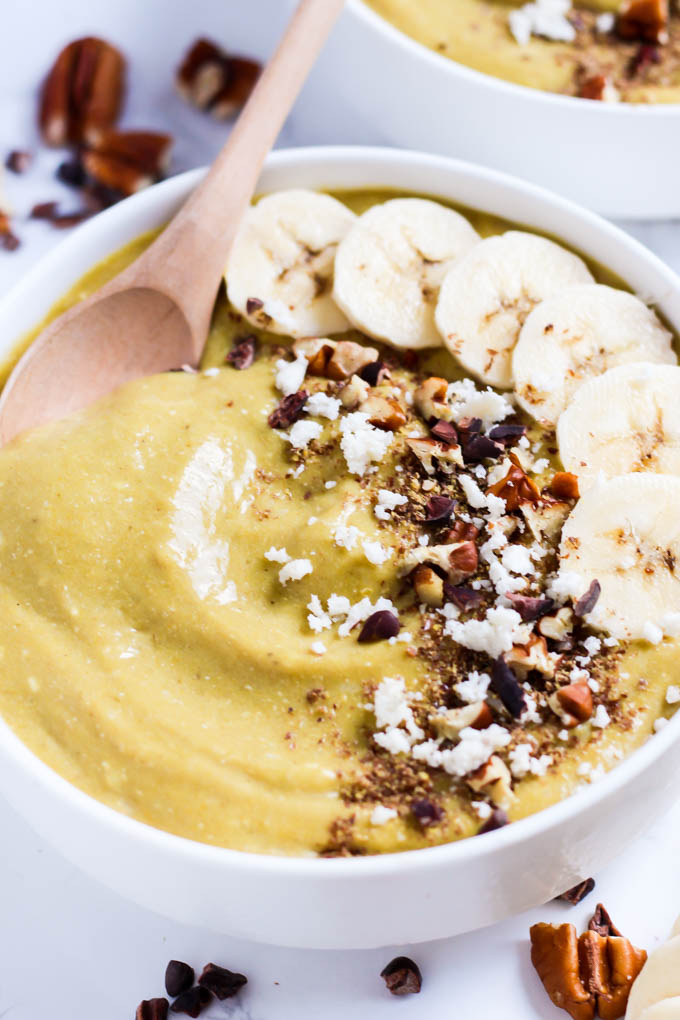 A banana smoothie bowl topped off with coconut flakes, cacao nibs, pecans and banana slices