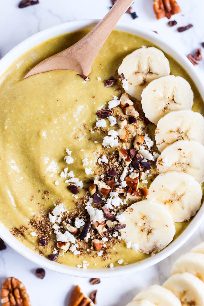 A smoothie bowl served with sliced banana, pecans, coconut and cacao nibs