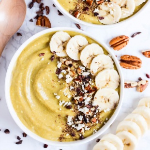 a smoothie bowl with bananas, coconut milk, turmeric and protein powder topped with bananas and pecans