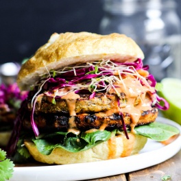 These vegan Asian Veggie Burgers are full of flavor & plant protein! Perfect for weekend grilling, topped with Mango Cabbage slaw and spicy Sriracha sauce.