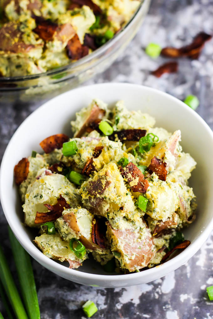 a single serving of vegan potato salad set next to the larger bowl of potato salad