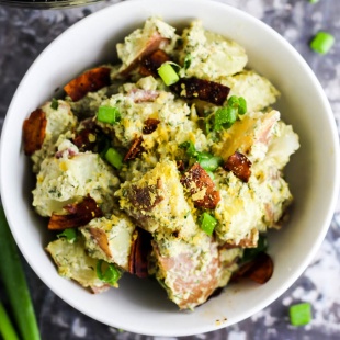 a bowl of dairy-free potato salad topped with coconut bacon and green onions