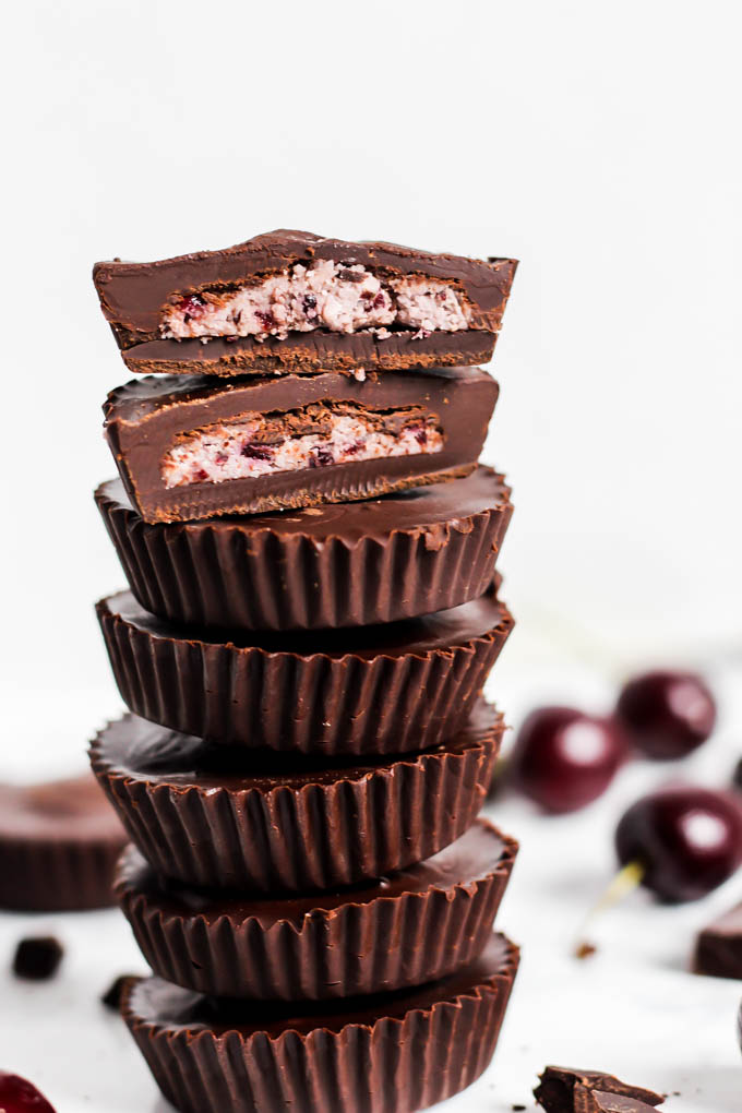 a halved cherry coconut butter cup on a stack of chocolate cups