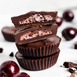 a batch of chocolate cherry coconut cups surrounded by fresh cherries