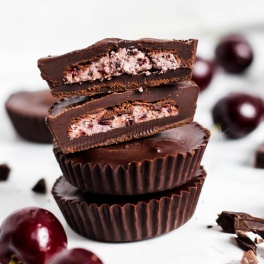 a batch of chocolate cherry coconut cups surrounded by fresh cherries