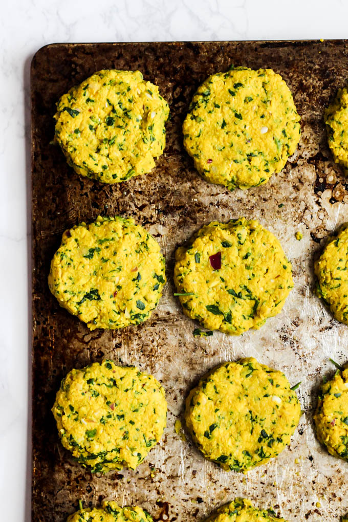 a sheet tray lined with 16 falafels, about to go into the oven to bake