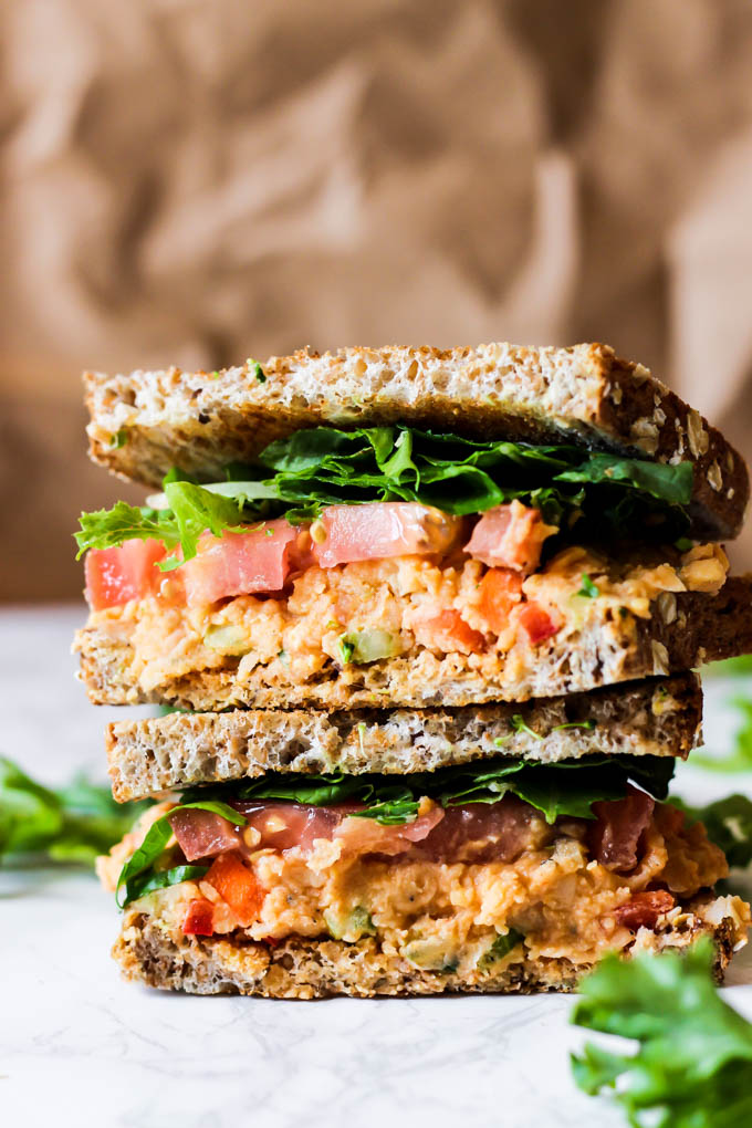 A vegan chickpea sandwich topped with lettuce and tomatoes