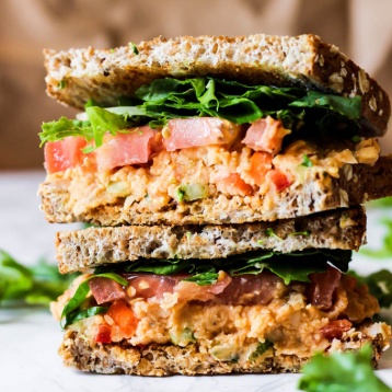 a sandwich with buffalo chickpea salad, lettuce and tomatoe